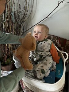 A cute baby sitting inside a woven basket.